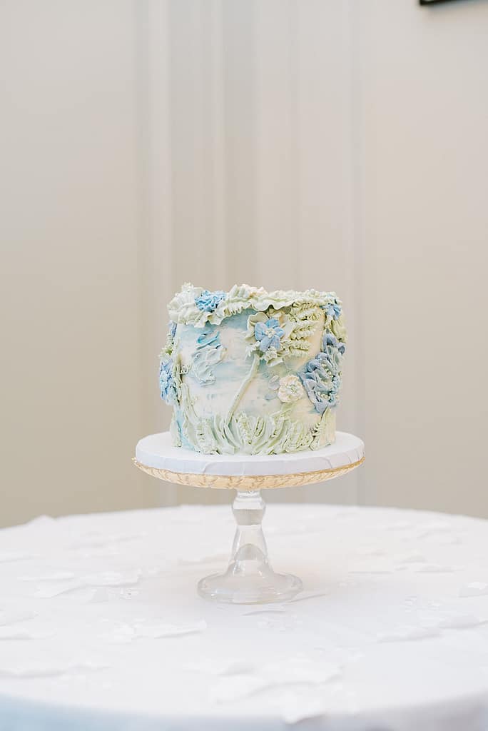 Eolia Mansion - Jennifer Conti Photography - small 6" cake on a clear cake server, the cake is embossed in buttercream in light greens and blues giving it a 3D textured look