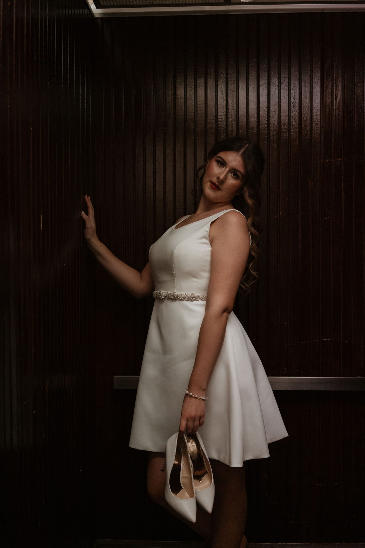bride holding heels in elevator