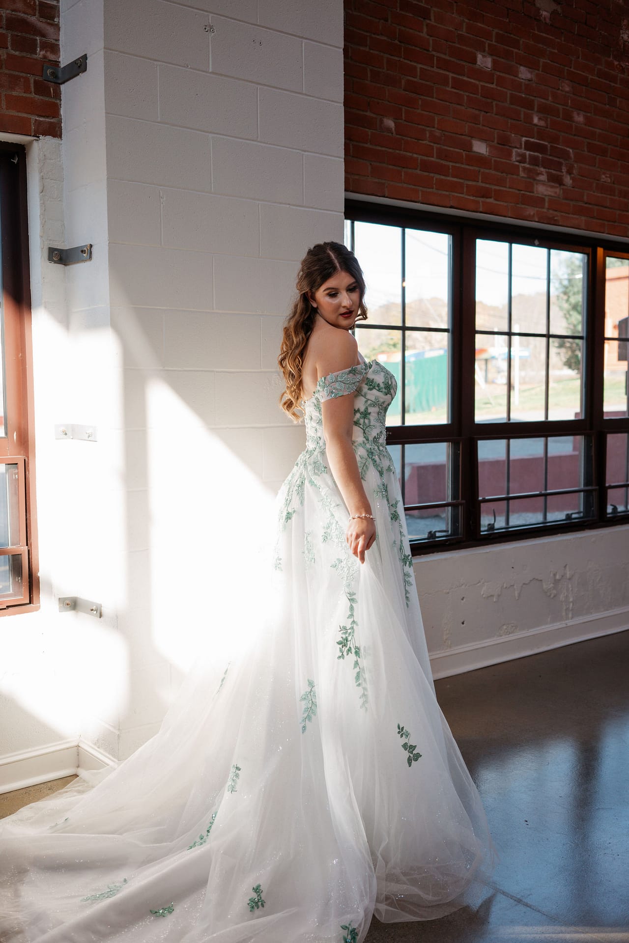 bride posing with greenery details on wedding dress