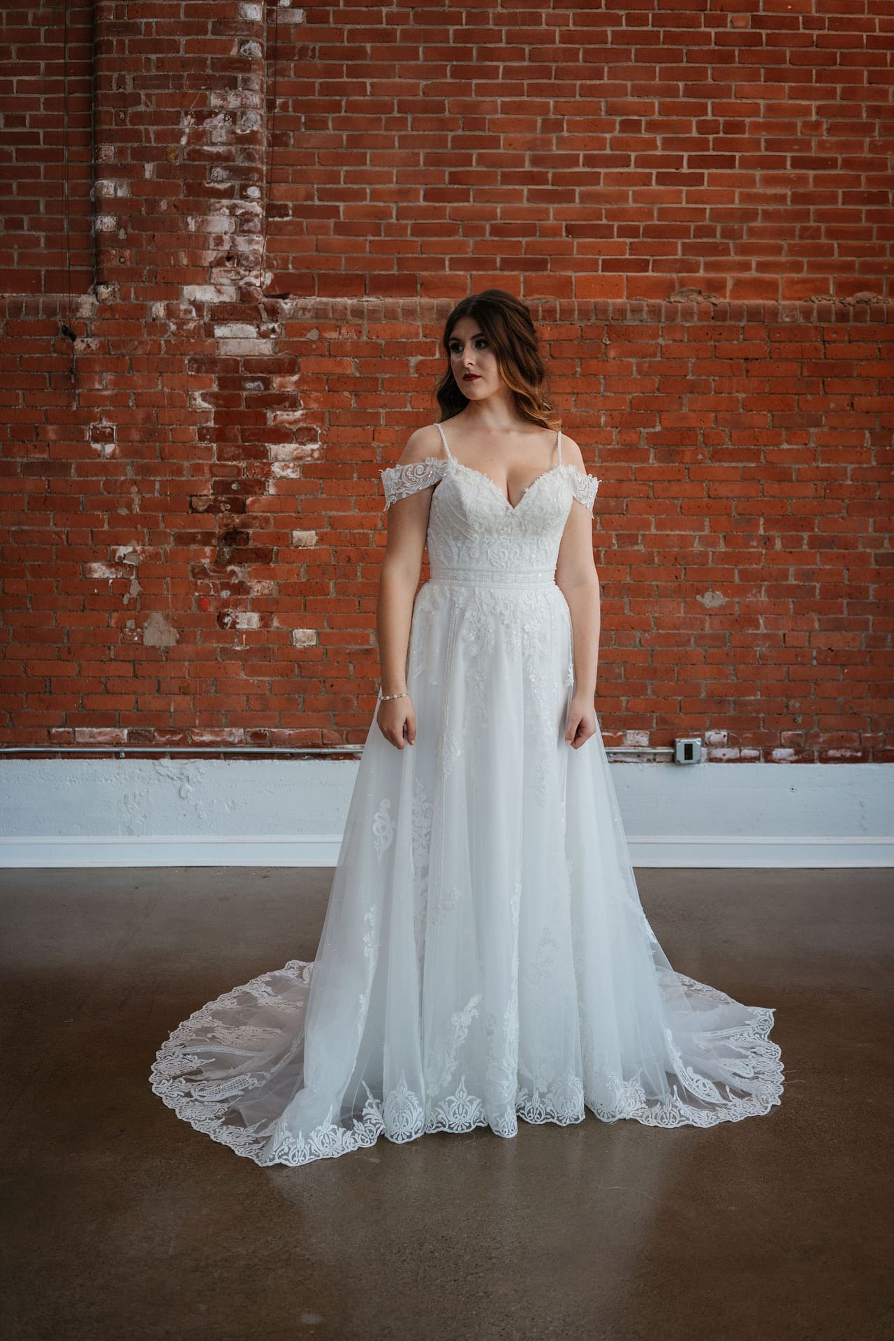 bride posing in her wedding dress in front of brick wall